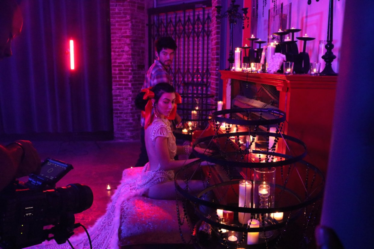 Candle-lit piano set with talent and camera op in red gel light